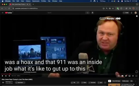 The image shows a video still from a YouTube clip featuring a man speaking into a microphone. He has short, dark hair and is wearing a black jacket over a green shirt. The man appears to be animated and expressive, with a serious facial expression as he gestures with his hands while speaking. 

In the background, there are multiple computer screens displaying various graphics and images, suggesting a media or broadcasting environment. One screen shows a smaller image of a crowd, possibly at an event, while the other screens have various data or video feeds. The setting is dimly lit, with a black backdrop that emphasizes the speaker and the screens.

At the bottom of the image, there are subtitles that read: "was a hoax and that 911 was an inside job what it's like to gut up to this." The text is in white and appears against a dark background, making it easily readable.

The video is hosted on YouTube, as indicated by the logo in the top left corner, and the video title is visible: "Alex Jones Says Trump Is Just The Start (HBO)" along with the channel name "VICE News" and its subscriber count of 9.22M. The interface includes standard YouTube controls for play, share, and download options.

Overall, the image captures a moment from a media presentation, highlighting the speaker's engagement with the topic at hand, while the background suggests a professional broadcasting setup.