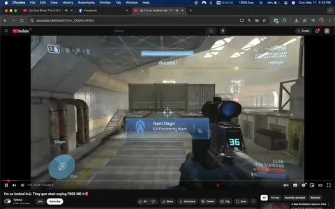 The image displays a screenshot from a YouTube video titled "I'm so locked in🔒 They gon start saying FREE ME.🚔" by a user named Tylenul, who has 5.48K subscribers. The video is currently playing, with a timestamp of 0:17 out of a total duration of 15:20. 

In the foreground, there is a first-person view from a video game, specifically from the game "Halo." The player is holding a weapon, which appears to be a futuristic firearm, and the weapon's display shows a blue light and the number "36." The game interface includes a blue circular icon indicating the player's position, with a distance marker of "25m." 

A prominent blue overlay in the center of the screen reads "Team Slayer" with the instruction "Kill the enemy team." Above this, there is a welcome message. The background features an industrial setting with large metal structures, pipes, and a staircase leading to an upper level. The environment is well-lit, with natural light streaming through large windows, creating a bright atmosphere.

The video player interface at the bottom includes standard controls such as play, pause, and volume settings, along with options to share, download, and clip the video. The browser window shows tabs for Facebook and other content, indicating the user is multitasking. 

Overall, the image captures a moment from a gaming video, showcasing both the gameplay and the YouTube interface.