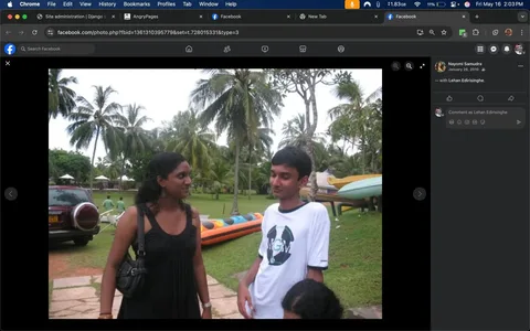 The image depicts two individuals standing in a grassy area with palm trees in the background. 

**People:**
1. **Female Individual:**
   - She is positioned on the left side of the image.
   - She has long, curly black hair and is wearing a sleeveless black dress that reaches her ankles.
   - She has a black shoulder bag slung over her left shoulder.
   - Her facial expression appears to be engaged as she looks towards the male individual.
   - She has earrings visible in her ears.

2. **Male Individual:**
   - He is on the right side of the image, slightly turned towards the female.
   - He has short black hair and is wearing a white t-shirt with a circular logo on the front, which includes the letters "MGM" in the center.
   - The shirt has black sleeves and a blue trim around the collar.
   - He is standing with one hand resting on his hip and appears to be looking down or slightly away from the female.

**Setting:**
- The background features a lush green lawn with several palm trees.
- There are two people in the distance, partially obscured, who appear to be engaged in an activity.
- In the background, there are colorful inflatable boats or kayaks, with one prominently orange and blue.
- A vehicle, possibly an SUV, is parked on the left side of the image, identifiable by its round rear light and dark color.
- The overall atmosphere suggests an outdoor recreational area, possibly near a beach or water activity site.

**Environmental Context:**
- The weather appears to be overcast, with a cloudy sky, indicating it may be a warm day.
- The setting seems to be casual and relaxed, likely a social gathering or outing.

No readable text, logos, or trademarks are visible in the image aside from the logo on the male's shirt. There are no identifiable public figures or brands present. The focus remains on the individuals and their immediate surroundings.