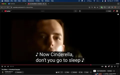 The image shows a still from a YouTube video featuring a male singer. His face is partially illuminated against a dark background, creating a dramatic effect. The singer has short, light brown hair and is looking directly at the camera. His expression appears serious and focused. 

At the bottom of the image, there are subtitles displayed in white text on a black background, reading: "Now Cinderella, don't you go to sleep." This text is part of the lyrics from the song being played in the video. 

The video player interface is visible, showing the play button, a timeline bar indicating the video's progress at 3:50 out of a total of 5:02 minutes, and options for liking, sharing, downloading, and clipping the video. Below the video, the channel name "The KillersMusic" is displayed, along with a subscriber count of 2.56 million. 

The video is titled "The Killers - A Dustland Fairytale," indicating that it is a music video from the band The Killers. The interface includes typical YouTube features such as a search bar, a logo in the top left corner, and various icons for user interaction. 

The overall setting is a digital environment, specifically a YouTube video playback interface, with no additional physical objects or locations visible in the frame. The focus remains on the singer and the lyrics displayed.