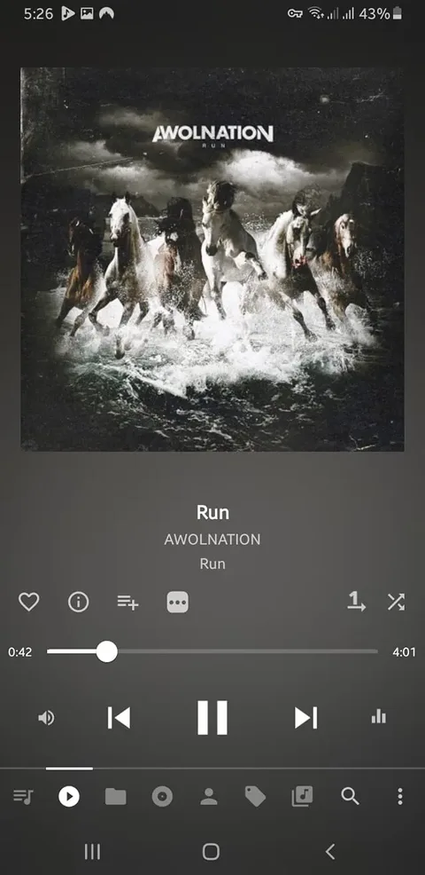 The image displays a music player interface featuring the song "Run" by AWOLNATION. The album cover is prominently displayed, showcasing a dramatic scene with several horses galloping through turbulent water. The horses are depicted in various colors, including white and brown, and are splashing through the waves, creating a sense of motion and energy. The background is dark and stormy, with clouds that suggest an ominous atmosphere.

At the top of the album cover, the band name "AWOLNATION" is written in bold, white capital letters. Below it, the title "RUN" is also displayed in a similar font style. The overall color scheme of the album cover is dark, with shades of black, gray, and white dominating the image, contributing to a dramatic and intense visual effect.

Below the album cover, the music player interface shows the song title "Run" and the artist "AWOLNATION" in a clear, white font. The playback progress bar indicates that the song is currently at 42 seconds, with a total duration of 4 minutes and 1 second. There are various playback controls visible, including play, pause, and skip buttons, as well as options for adding the song to a playlist or sharing it.

The device's status bar at the top indicates the time (5:26), battery level (43%), and signal strength, suggesting that this is a mobile device displaying the music player interface. The overall layout is clean and user-friendly, focusing on the music experience.